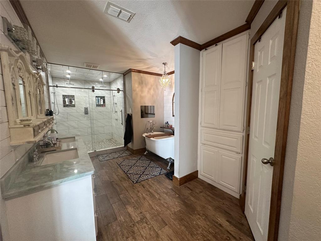 101 Twin Creek Road Comanche, TX 76442 - Photo 26 of 28 Bathroom with a stall shower, a freestanding tub, a textured ceiling, dark wood-style floors, and vanity