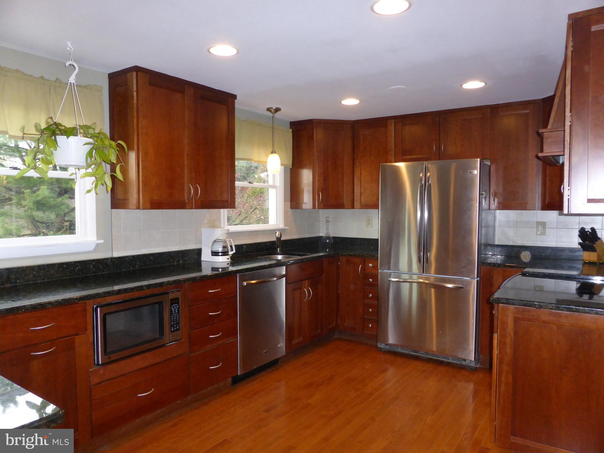 9107 Bowline Road Baltimore, MD 21236 - Photo 7 of 19 a kitchen with stainless steel appliances granite countertop a refrigerator a sink a stove a microwave and wooden cabinets