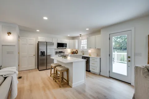 a kitchen with a refrigerator a stove top oven a sink dishwasher and white cabinets with wooden floor