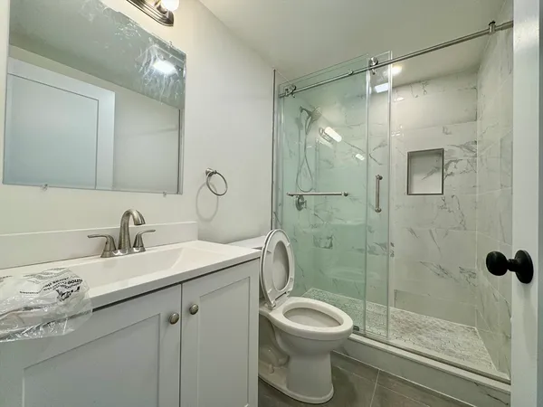 a bathroom with a granite countertop sink a toilet and shower