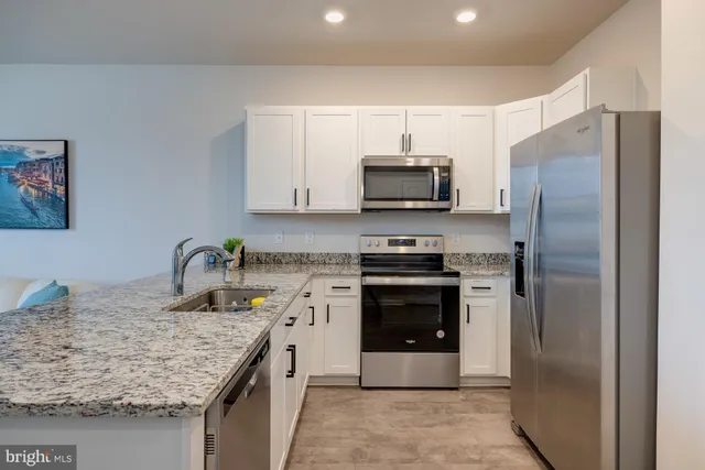 a kitchen with granite countertop a stove top oven microwave and cabinets
