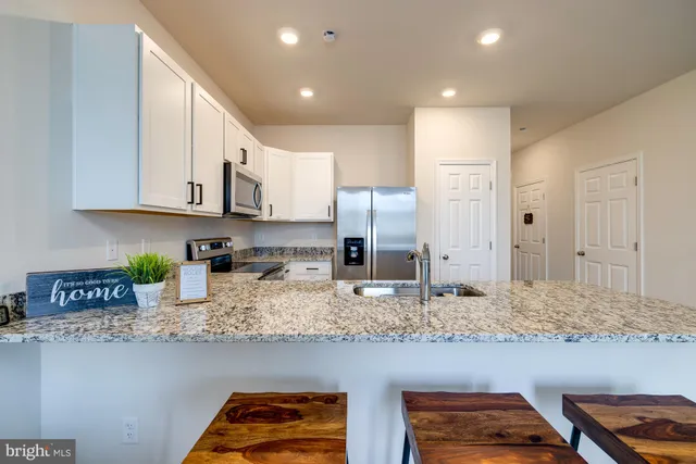 a kitchen with granite countertop a sink a stove and cabinets