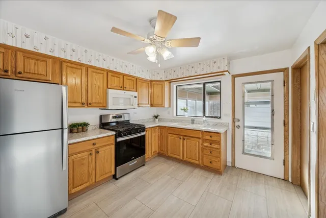 a kitchen with stainless steel appliances granite countertop a refrigerator a sink dishwasher a stove with wooden cabinets and floors