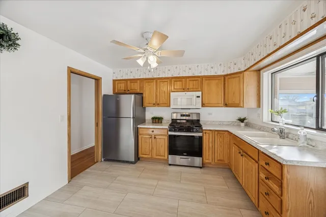 a large kitchen with stainless steel appliances granite countertop a stove refrigerator and a sink