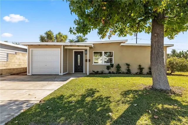 a view of a house with backyard and a tree