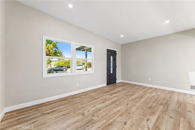 a view of an empty room with window and wooden floor