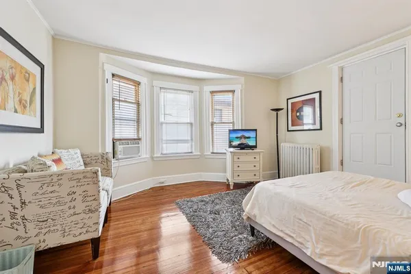 a spacious bedroom with a bed a dresser and next to a window