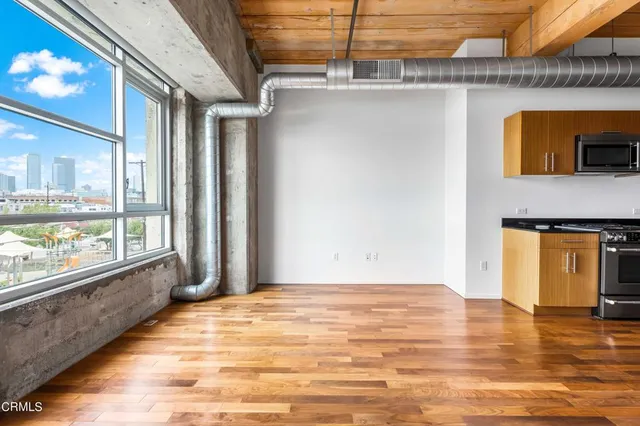 a view of an empty room with window and wooden floor