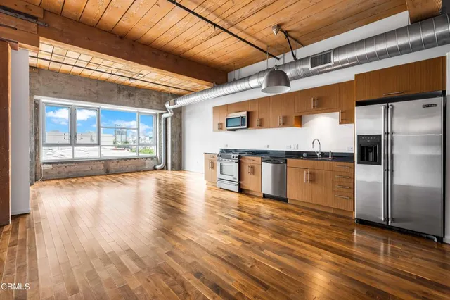 a kitchen with stainless steel appliances granite countertop a refrigerator a stove and a wooden floors