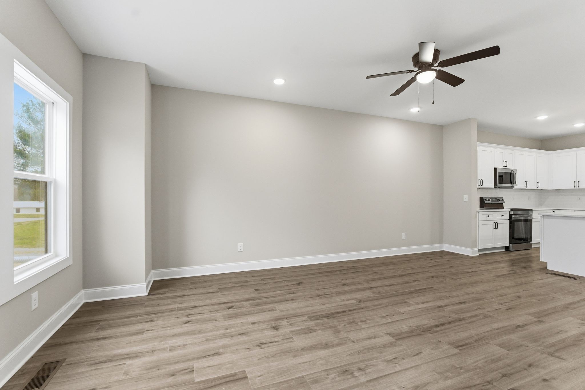 263 West Spring Street Smithville, TN 37166 - Photo 4 of 23 an empty room with wooden floor a ceiling fan and windows