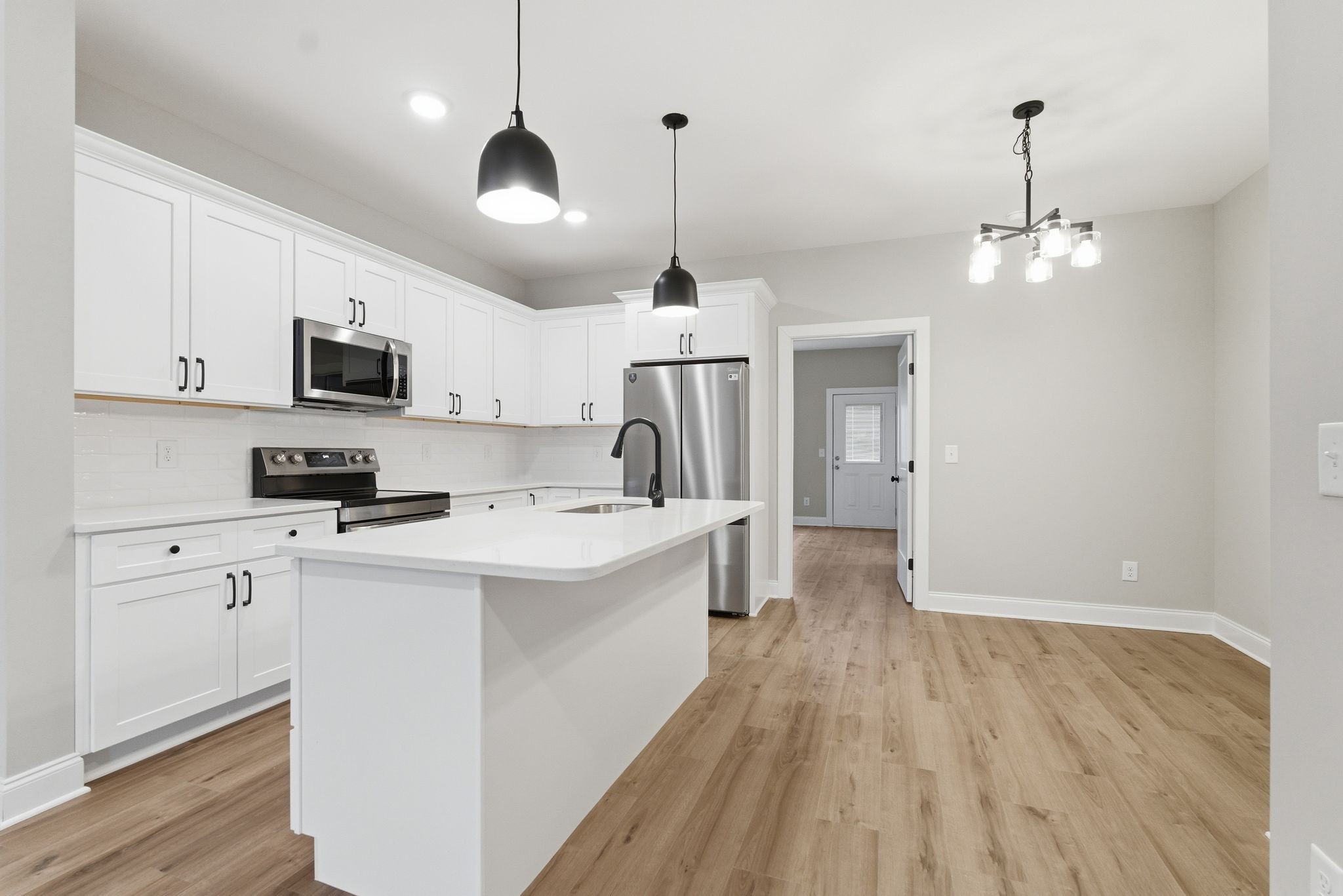 263 West Spring Street Smithville, TN 37166 - Photo 9 of 23 a kitchen that has a microwave a stove a sink dishwasher a refrigerator and white cabinets with wooden floor