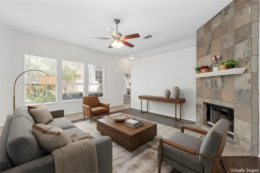4202 Timberglen Road Dallas, TX 75287 - Photo 16 of 40 Spacious living area featuring a stone-clad fireplace with a decorative mantel, multiple windows, and a ceiling fan with integrated lighting