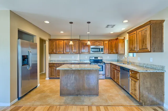 a kitchen with stainless steel appliances granite countertop a stove a sink a refrigerator and a oven