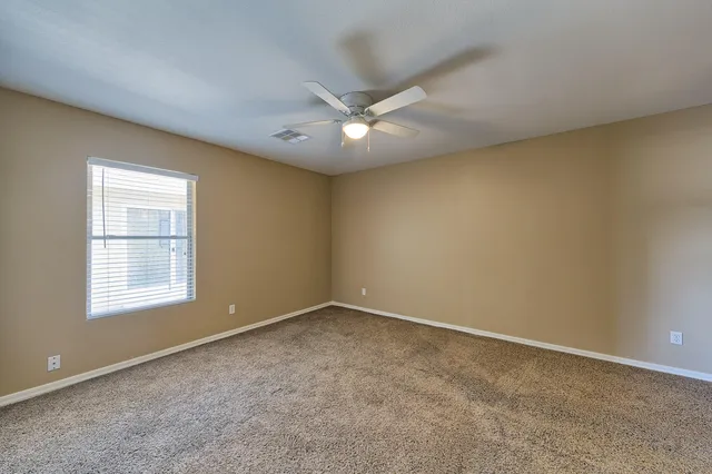 an empty room with a window and a ceiling fan