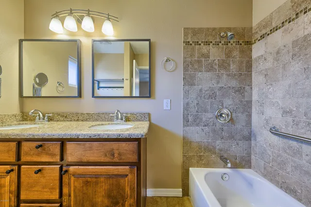 a bathroom with a granite countertop sink a mirror a bathtub and shower