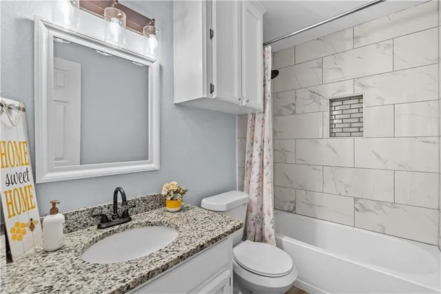 a bathroom with a granite countertop sink toilet mirror and shower
