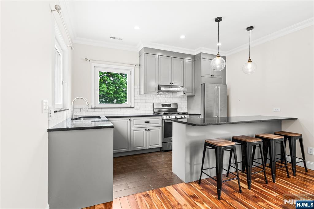 346 Cleveland Avenue, Unit 2 Hasbrouck Heights, NJ 07604 - Photo 17 of 39 a kitchen with stainless steel appliances granite countertop a stove a sink a microwave a refrigerator and white cabinets with wooden floor