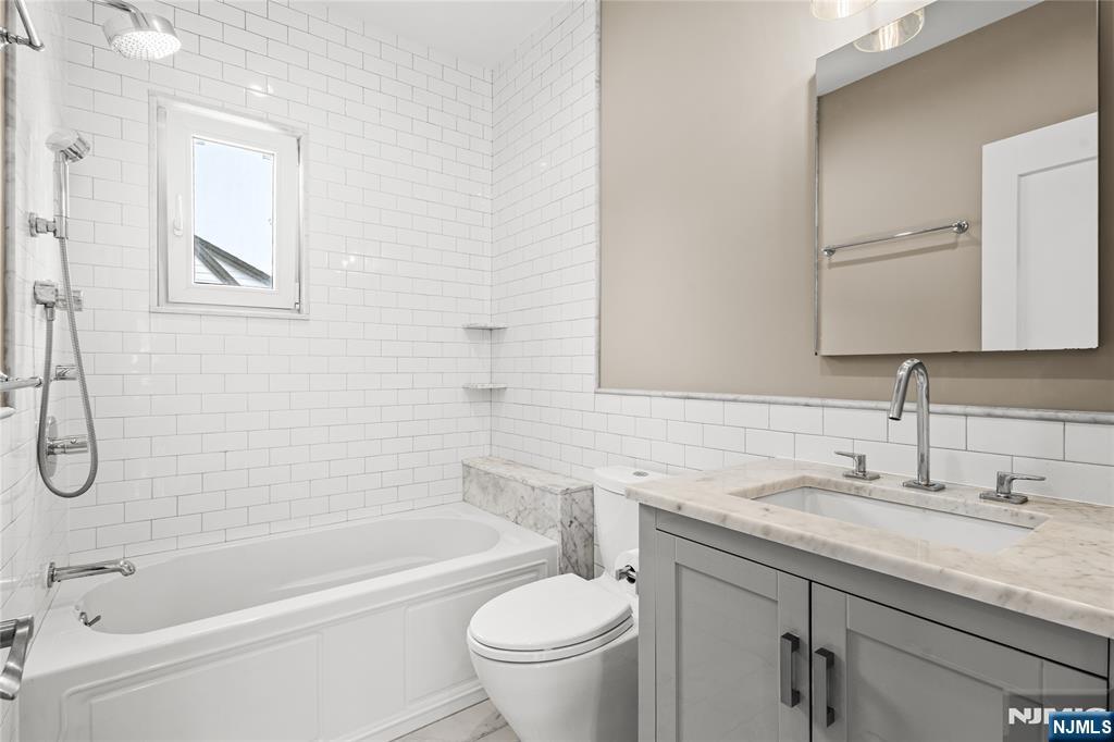 346 Cleveland Avenue, Unit 2 Hasbrouck Heights, NJ 07604 - Photo 20 of 39 a bathroom with a granite countertop sink a toilet and a bathtub