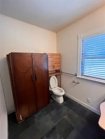 a white toilet sitting next to a bathroom sink and a window