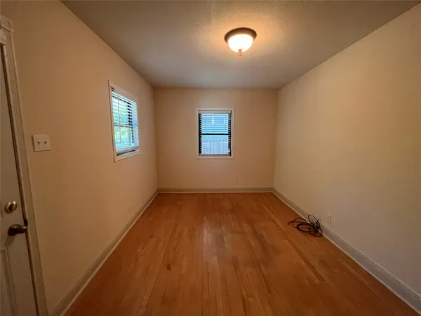 an empty room with a hardwood and windows
