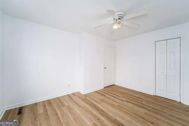 a view of empty room with wooden floor and fan