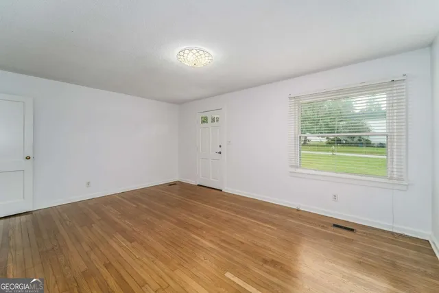 a view of an empty room with wooden floor and a window