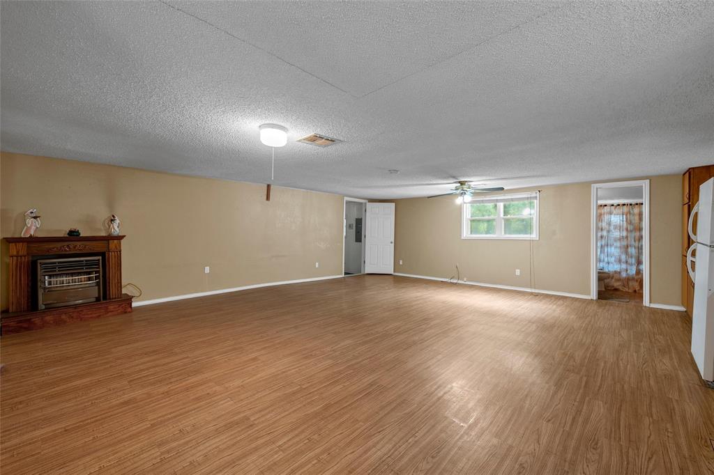 4704 Williams Road Bellmead, TX 76705 - Photo 3 of 32 Spacious interior room featuring wood-finish flooring, a built-in fireplace with a decorative mantel, a ceiling fan, and ample natural light from the window