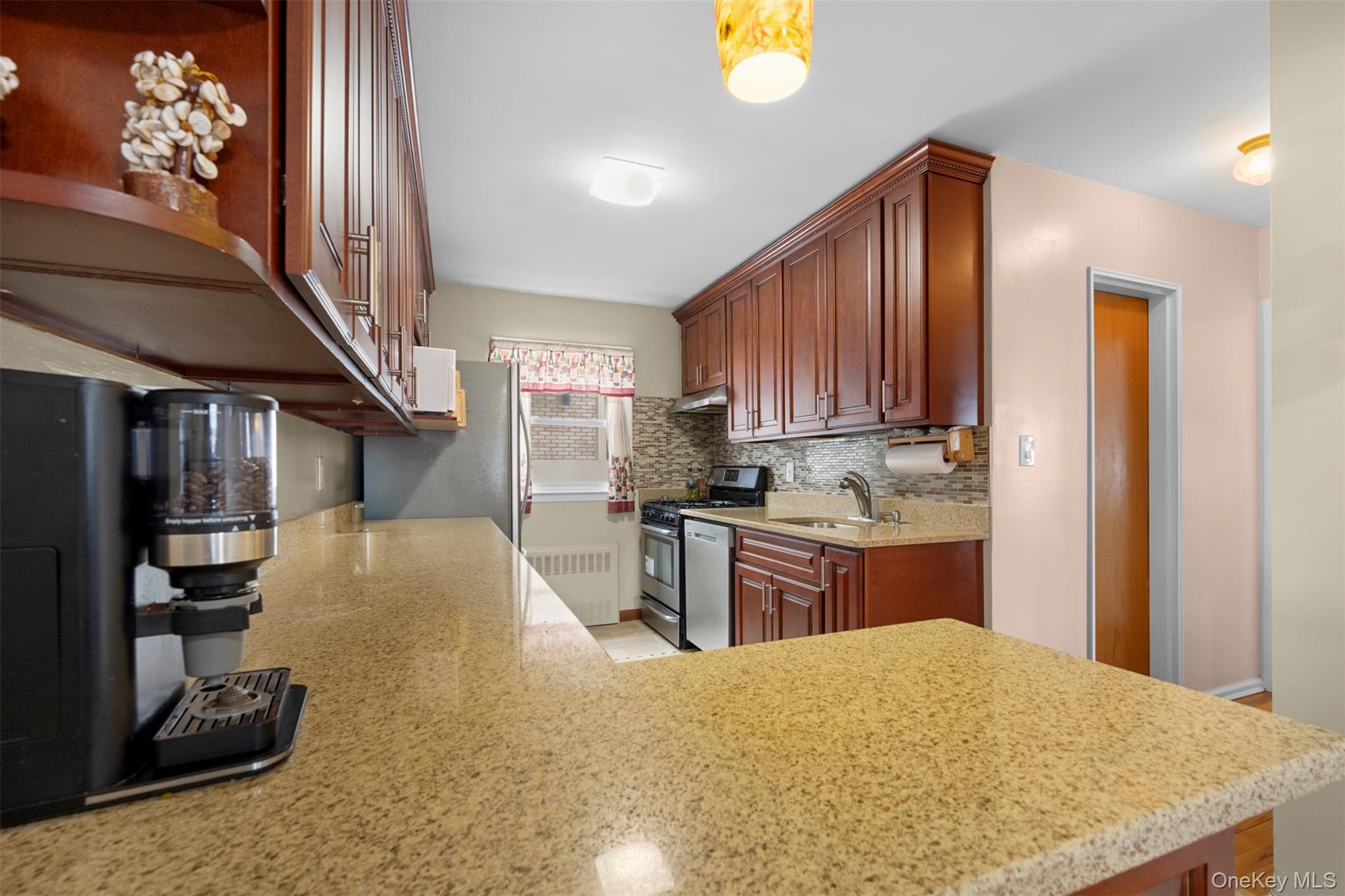 8807 Sabre Street Queens, NY 11427 - Photo 8 of 29 a kitchen with kitchen island granite countertop wooden cabinets a sink stainless steel appliances and a window