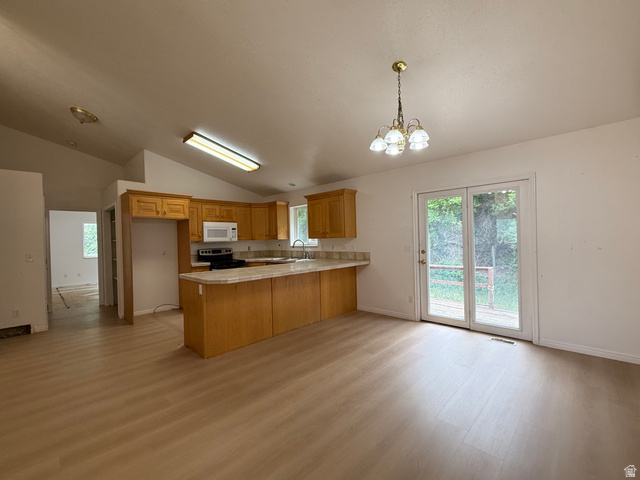 838 East Mountain Road Logan, UT 84321 - Photo 14 of 37 Open-concept kitchen and dining area featuring wood-finish flooring, vaulted ceilings, and a light wood cabinetry kitchen with a built-in microwave