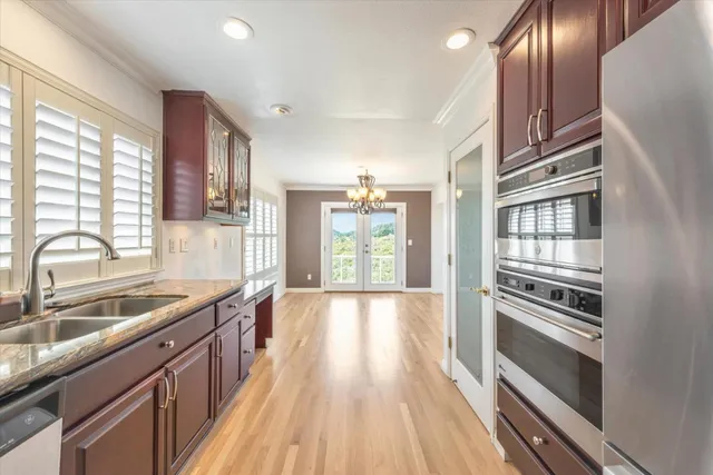 a kitchen with granite countertop stainless steel appliances a sink window and cabinets