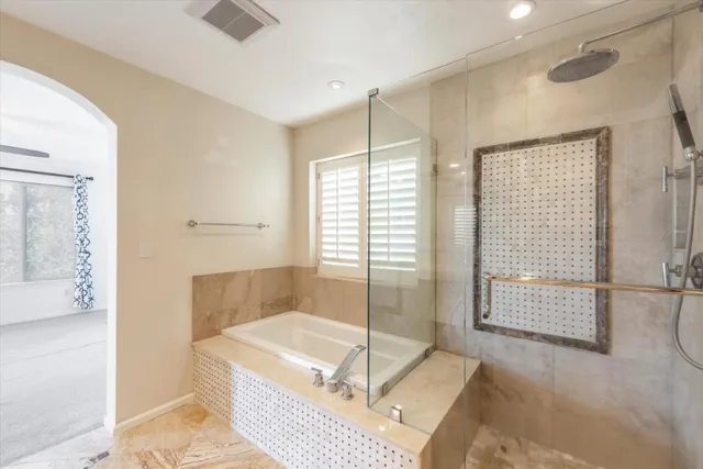a spacious bathroom with a tub shower and mirror