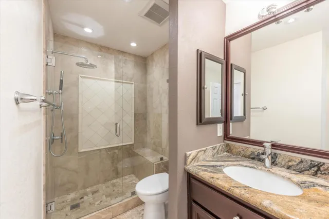 a bathroom with a granite countertop sink a toilet a mirror and shower