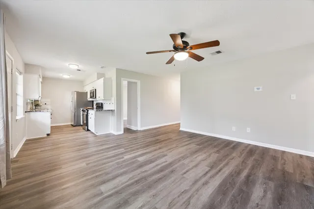 a view of empty room with wooden floor and ceiling fan