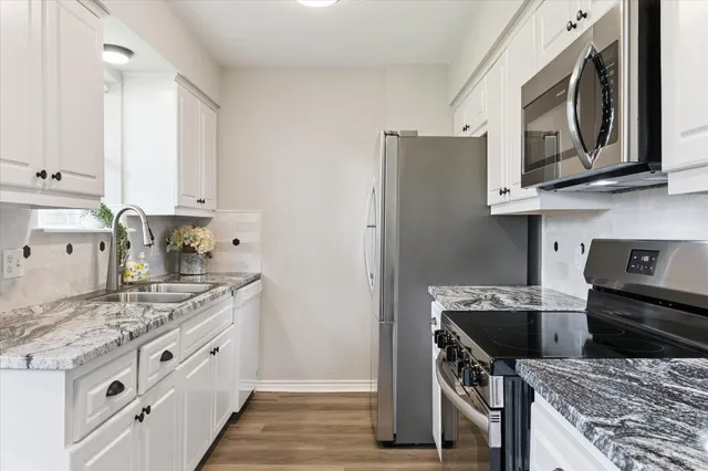 a kitchen with stainless steel appliances granite countertop a stove a sink and a microwave