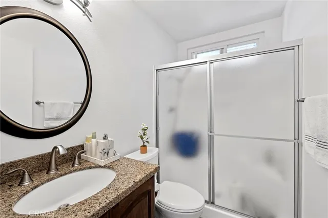 a bathroom with a granite countertop sink toilet mirror vanity and shower
