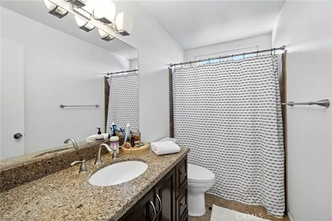 a bathroom with a granite countertop sink a toilet a mirror and shower curtain