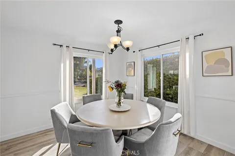 a dining room with wooden floor a chandelier a wooden table and chairs