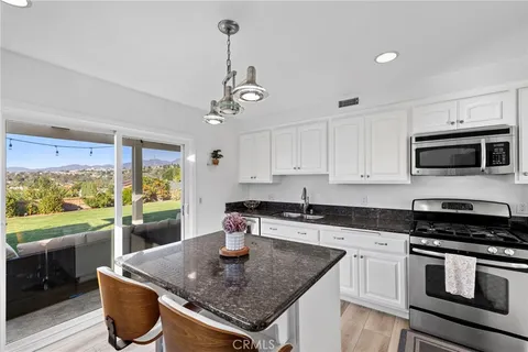 a kitchen with stainless steel appliances granite countertop a sink a stove and a wooden cabinets