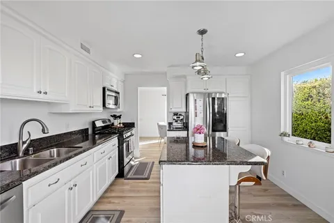 a kitchen with kitchen island granite countertop a sink stainless steel appliances and cabinets