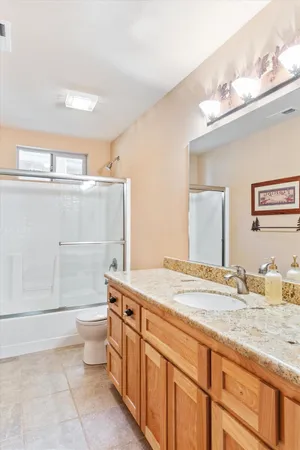 a bathroom with a granite countertop sink mirror vanity and toilet