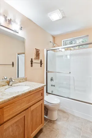 a bathroom with a granite countertop sink toilet and shower