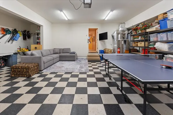a living room with a black white checkered floor with a gaming machine and dining chairs
