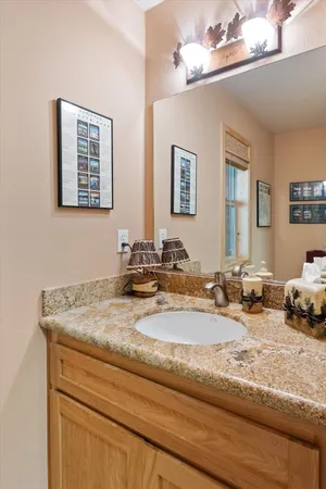 a bathroom with a granite countertop sink a mirror and vanity