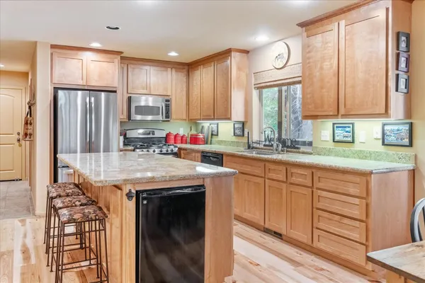 a kitchen with kitchen island granite countertop a sink appliances cabinets and a counter top space