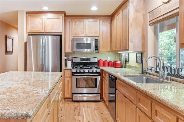 a kitchen with stainless steel appliances granite countertop a sink stove and refrigerator