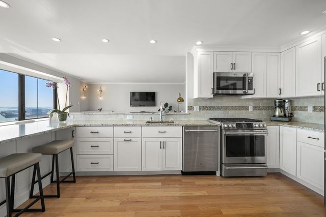 a large kitchen with stainless steel appliances lots of counter space and wooden floors