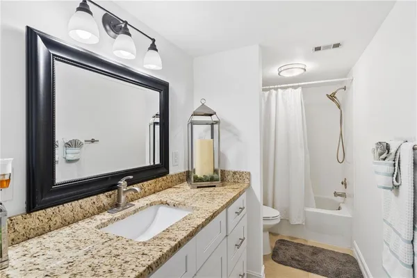 a bathroom with a granite countertop sink vanity mirror and shower