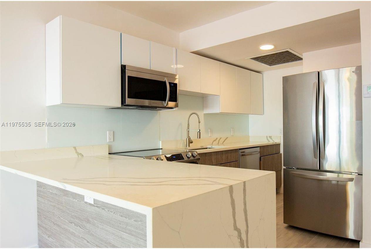 1000 7th Street Miami Beach, FL 33139 - Photo 16 of 36 a kitchen with a sink a microwave a refrigerator and cabinets