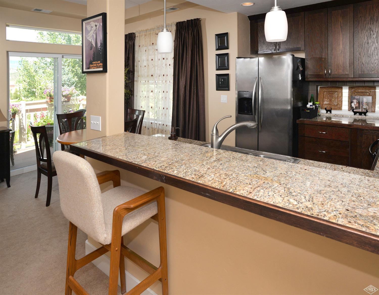 80 Freestone Road, Unit B201 Eagle, CO 81631 - Photo 8 of 15 a kitchen with stainless steel appliances granite countertop a table chairs and refrigerator
