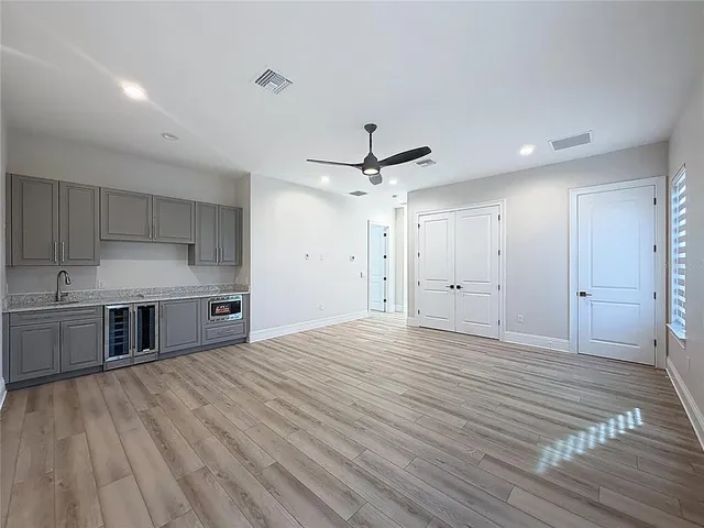 a view of a kitchen with stainless steel appliances a sink and wooden floor